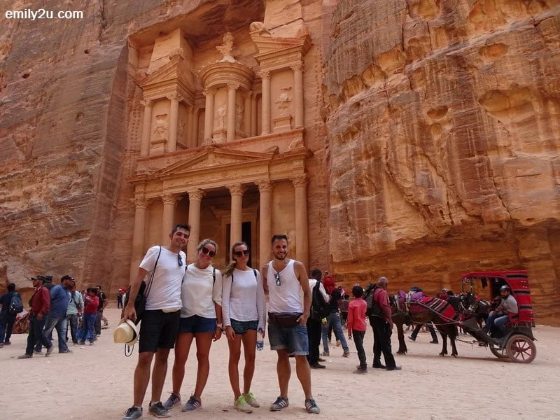 16. a group of tourists poses for a photo in front of The Treasury