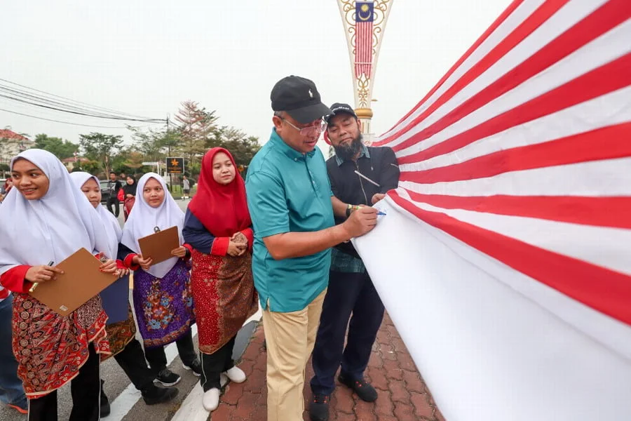 Ipoh City Mayor Dato’ Ahmad Suaidi Abdul Rahim places his signature on the Malaysian flag
