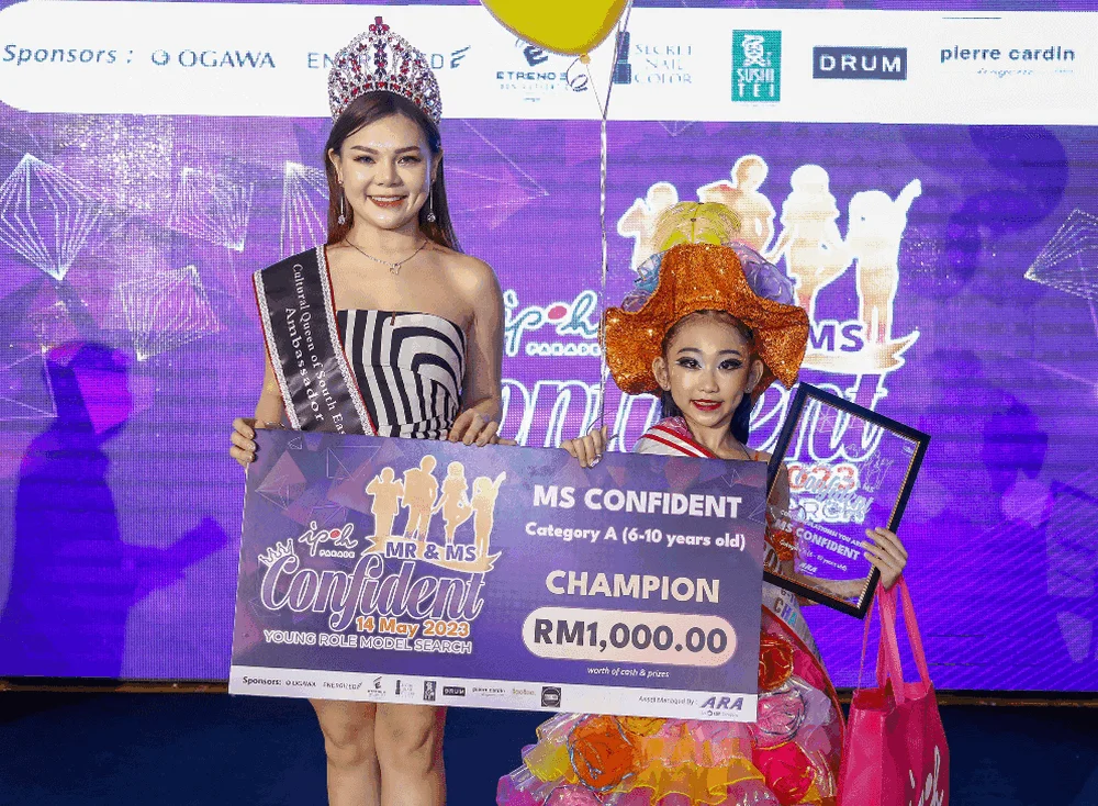 Ms Confident (6-10 years old) Kimberly Ng (R) receives the award from Emma Chung, ambassador of Cultural Queen Of SouthEast Asia