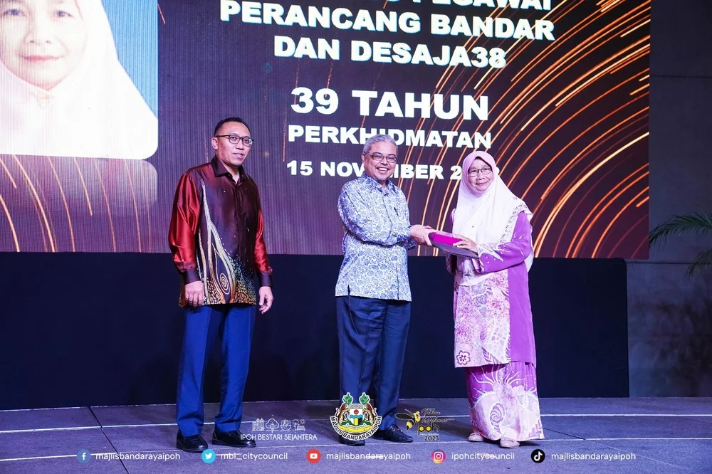 Ipoh City Mayor Y.Bhg. Dato' Rumaizi bin Baharin@Md Daud (M) presents a certificate of appreciation and souvenir to a MBI retiree (R)