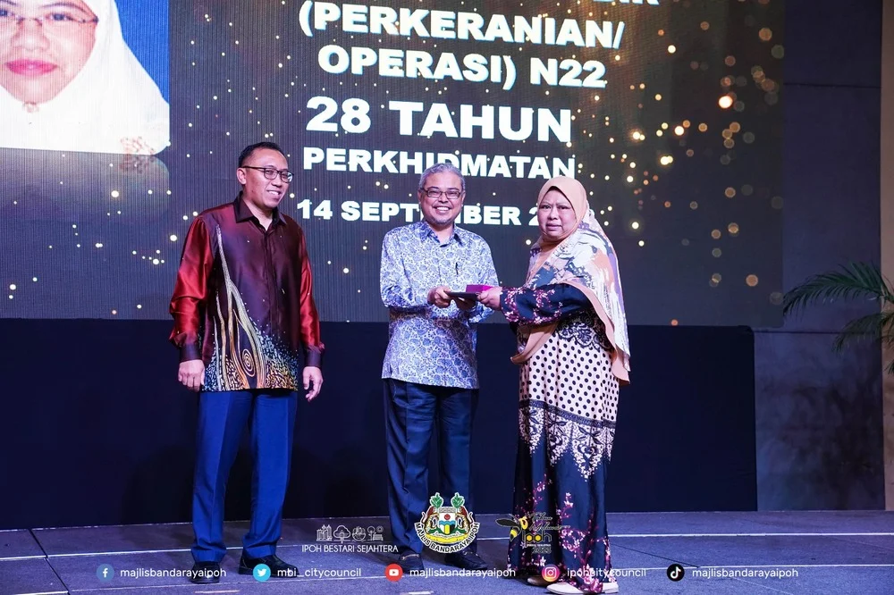 Ipoh City Mayor Y.Bhg. Dato' Rumaizi bin Baharin@Md Daud (M) presents a certificate of appreciation and souvenir to a MBI retiree (R)